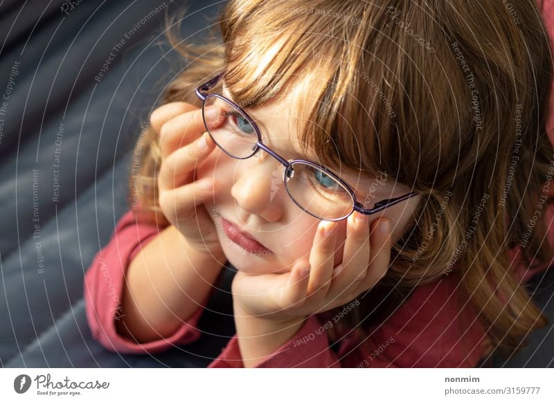 Junges blauäugiges Mädchen mit Brille, das ins Licht schaut. schön Kind Baby Kindheit Auge blond Denken klein niedlich Konzentration unschuldig jung Tochter