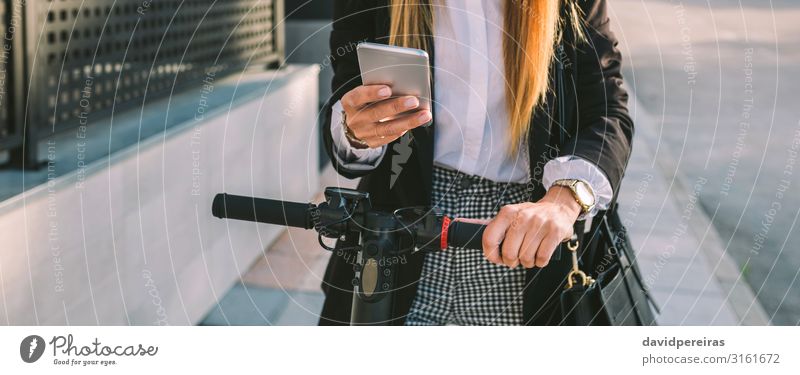 Nicht erkennbare Geschäftsfrau mit E-Scooter beim Blick auf das Handy elegant Stil schön PDA Internet Mensch Frau Erwachsene Verkehr Straße Mode modern