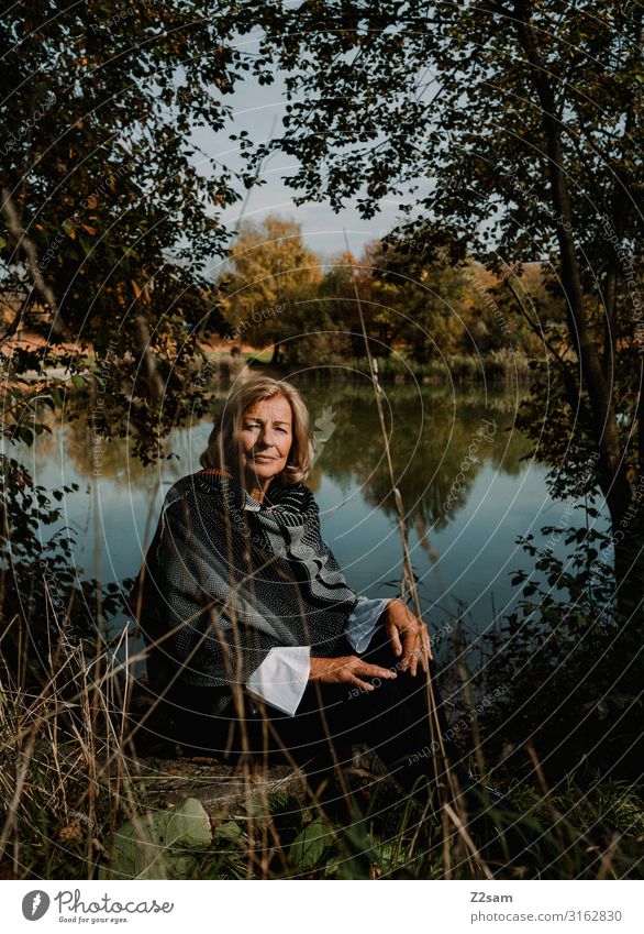 Herbstportrait Lifestyle Frau Erwachsene Weiblicher Senior 45-60 Jahre 60 und älter Natur Landschaft Schönes Wetter Sträucher Wald Seeufer Jacke Schal blond