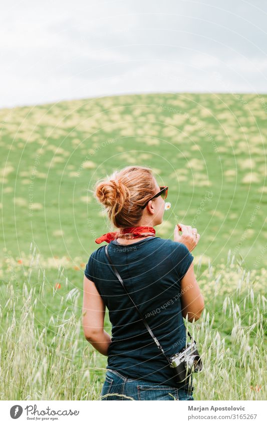 Junge Frau riecht Blume auf dem Feld Lifestyle Freude Ferien & Urlaub & Reisen Tourismus Abenteuer Freiheit Sommerurlaub Fotokamera Mensch feminin Jugendliche