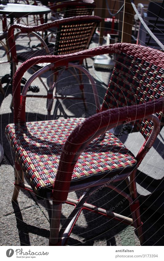 Korbstuhl auf einer Sonnenterrasse in einem Strassencafe sonne schatten draußen sonnenschein korbgeflecht Menschenleer Außenaufnahme Gastronomie Schatten