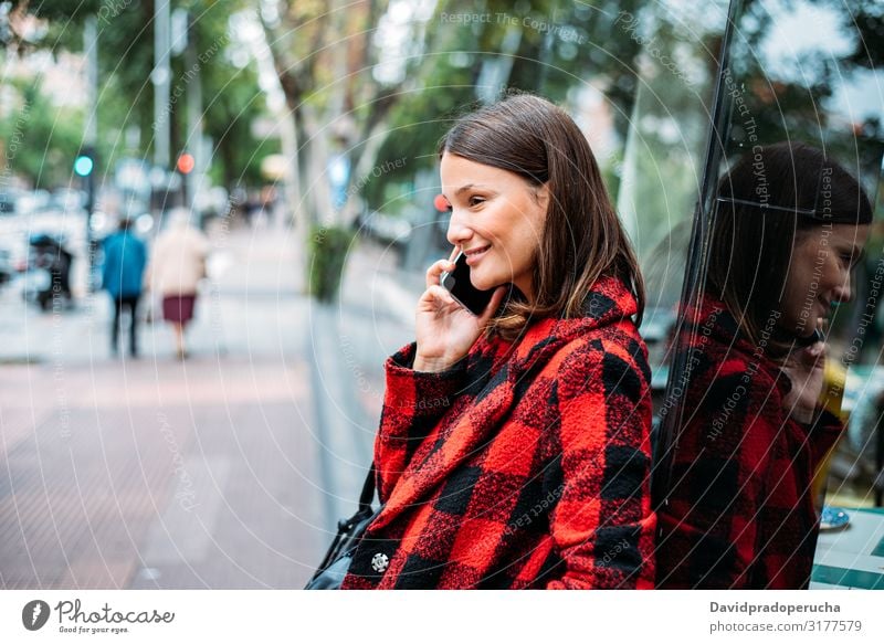 hübsche junge Frau steht auf Glas auf der Straße mit Smartphone Zelle benutzend Technik & Technologie Lächeln Tageslicht Wegsehen Gerät Apparatur Gespräch