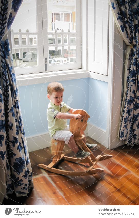 Kleiner Junge reitet auf einem alten Schaukelpferd Freude Spielen Kind Baby Kleinkind Kindheit Pferd Spielzeug Holz sitzen niedlich retro braun Kaukasier