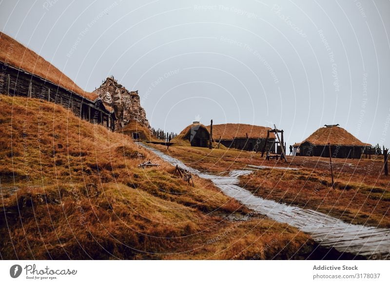 Dorf am grasbewachsenen Hang Hügel Berghang Wege & Pfade Hütte grau Himmel Landschaft Aussicht Natur Haus Hütten Jahreszeiten ländlich rustikal Umwelt Tradition