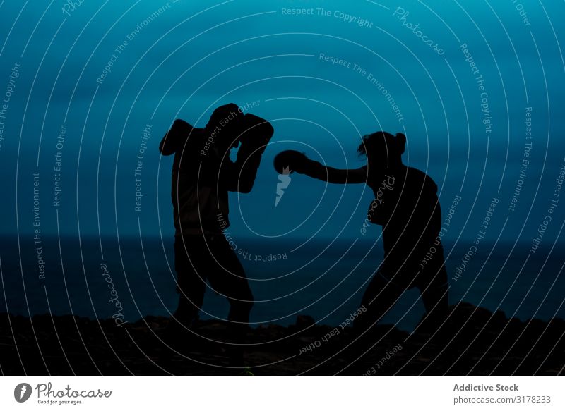Anonyme Kickboxer, die nachts kämpfen. Leichtathlet Kickboxen Fitness Silhouette tretend Gefecht Meer Himmel dunkel Abend Sport Erwachsene üben wettbewerbsfähig