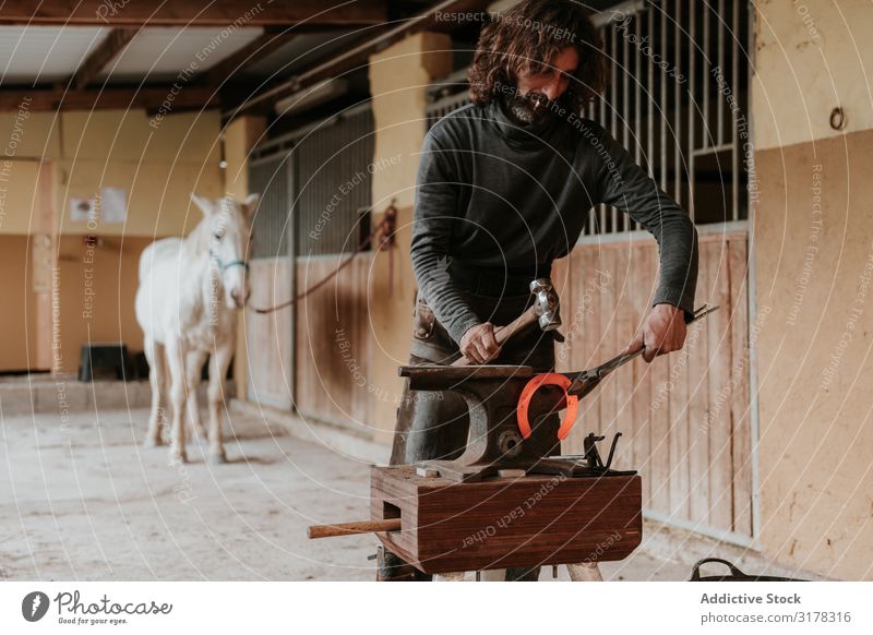 Schmiedeschmiede Hufeisen in der Nähe des Stalls Hufschmied Hammerschmiede Pferdestall Ranch Amboss Handwerk Eisen Zange heiß Mann Erwachsene professionell