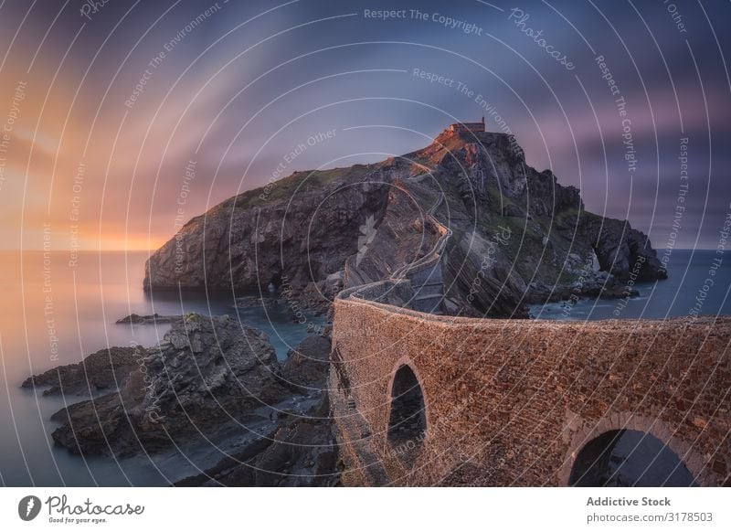 Einsame felsige Insel mit Kapelle und Steinbrücke Felsen Sonnenuntergang san juan gaztelugatxe Spanien Brücke Natur Küste Landschaft Langzeitbelichtung Wasser