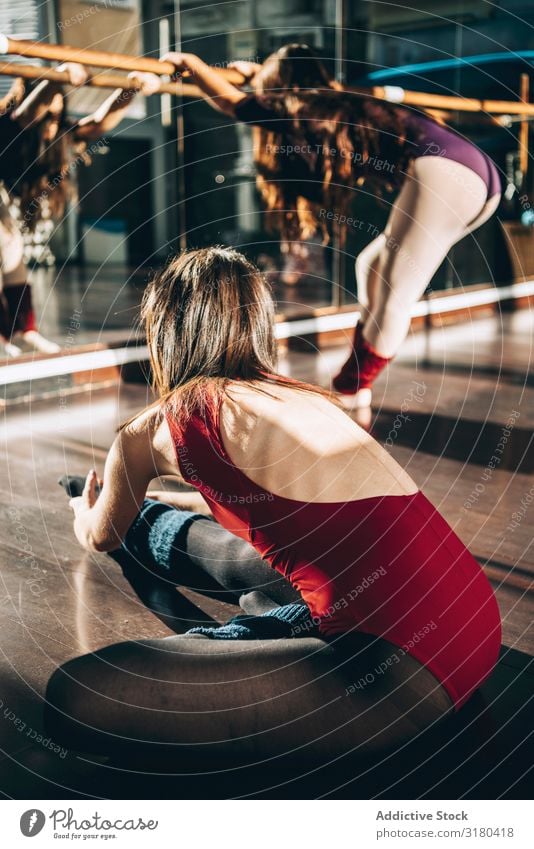 Junge Tänzerinnen und Tänzer trainieren gemeinsam im Studio beim Aufwärmen und Beugen im Sonnenlicht. Frau Balletttänzer Fitness üben Flexibilität Dehnung