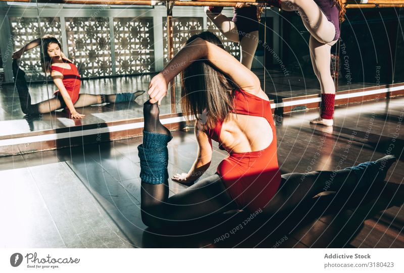 Zwei konzentrierte Frauen, die sich in der sonnigen Klasse vor dem Spiegel aufwärmen. Tänzerinnen strecken Studioaufnahme üben Sportbekleidung Partner Dehnung