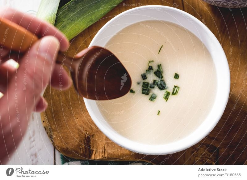 Gerte Hand mit Löffel und leckerer Vichyssoise Suppe auf Holztisch mit Lauch Vorspeise Schalen & Schüsseln Creme cremig Diät Lebensmittel Franzosen frisch