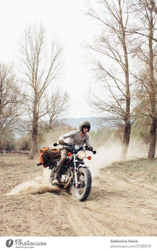 Mann fährt Motorrad auf staubiger Straße Ausritt Natur Ferien & Urlaub & Reisen Baum laublos Staub Landschaft Ausflug Verkehr Fahrzeug Laufwerk Freiheit