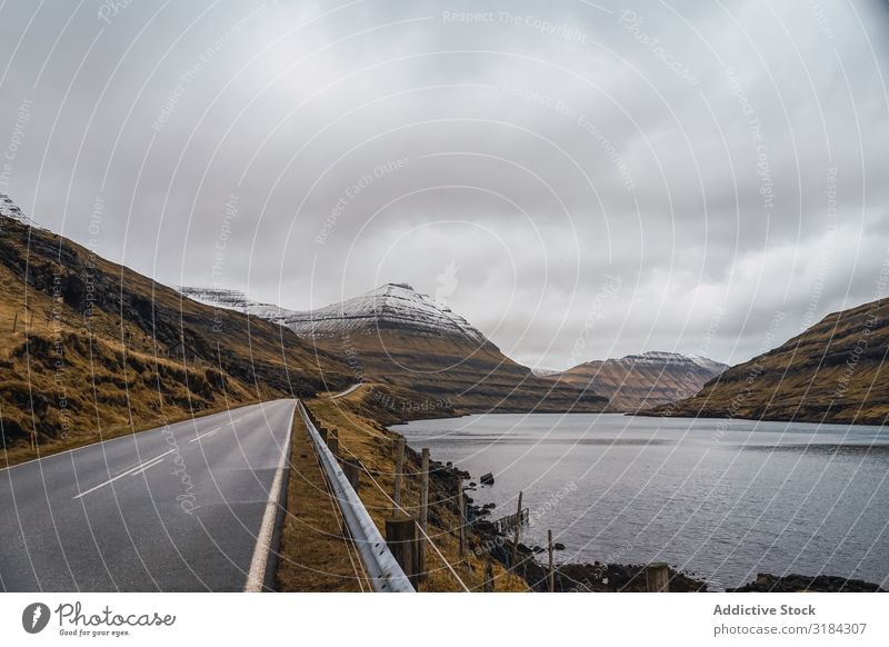 Wendelnde Straße auf hügeligem Gelände Hügel Landschaft geschlängelt Wolken Himmel Føroyar Ferien & Urlaub & Reisen Asphalt Wetter Natur ländlich Menschenleer