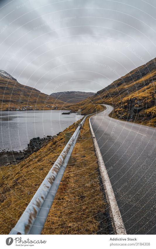 Wendelnde Straße auf hügeligem Gelände Hügel Landschaft geschlängelt Wolken Himmel Føroyar Ferien & Urlaub & Reisen Asphalt Wetter Natur ländlich Menschenleer