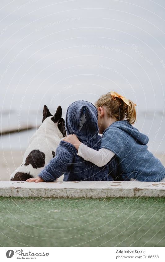 Kinder umarmender Hund am Strand Freundschaft Liebe Umarmen Haustier Meer sitzen gehorsam Baby französische Bulldogge lässig Lifestyle Freizeit & Hobby ruhen