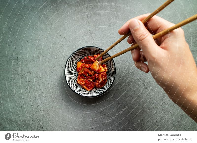 Die Hand des Mannes benutzt Essstäbchen, um Kimchi zu nehmen. Koreanische Küche. Gemüse Ernährung Mittagessen Abendessen Vegetarische Ernährung Asiatische Küche