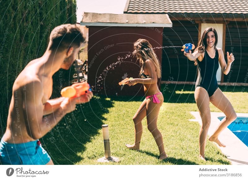 Freunde beim Spritzen mit Wasserpistolen Freundschaft platschen Pistole Beckenrand Mann Frau Freude Sommer Glück Freizeit & Hobby Jugendliche Geplätscher