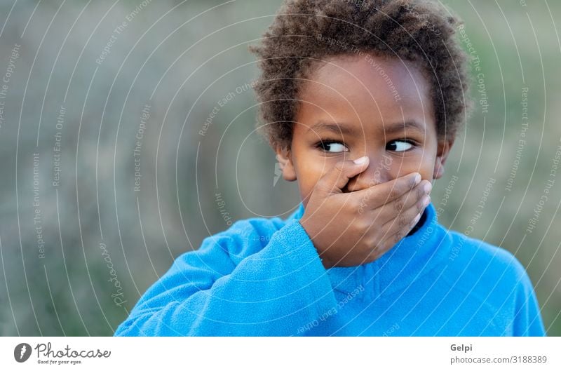 Kleiner afrikanischer Junge, der seinen Mund mit einem blauen Trikot bedeckt Glück schön Gesicht Windstille Kind Schulkind Mensch Mann Erwachsene Kindheit