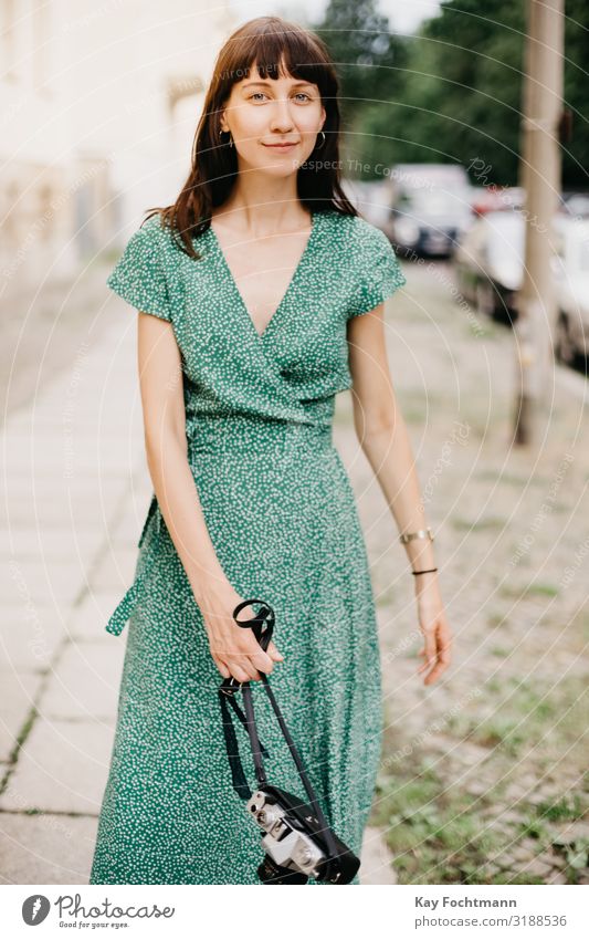 elegante Frau in grünem Kleid geht mit einer alten Filmkamera in der Hand Aktivität analog Schönheit Fotokamera erfassend Kaukasier entdeckend Europäer erkunden