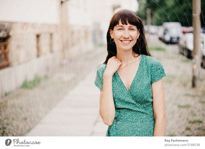 Eine Frau in einem eleganten grünen Kleid lächelt in die Kamera Erwachsener attraktiv schöne Frau charmant schick Großstadt klassisch Bekleidung selbstbewusst