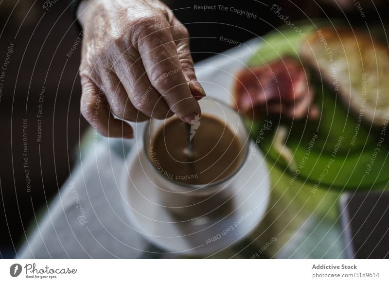 Hand der alten Frau, die den Löffel in der Tasse hält. rühren Kaffee trinken Frühstück Getränk heiß Lebensmittel Morgen Mensch Senior Tisch aromatisch Koffein