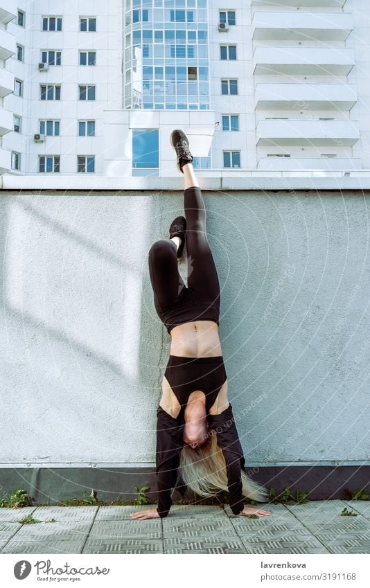 Junge erwachsene blonde Frau, die einen Handstand im Freien macht. Großstadt Kerngehäuse Yoga dünn Körper sportlich muskulös Junge Frau Aktion Kraft Training