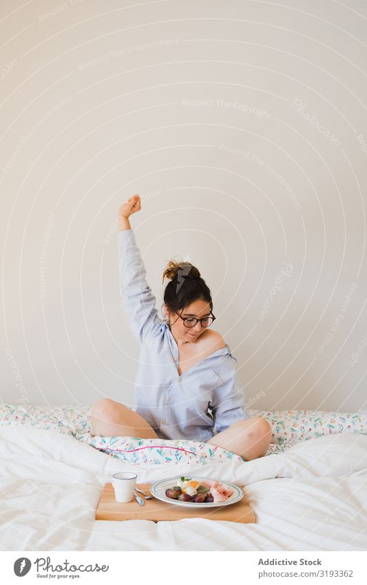 Junge Frau mit Frühstück auf dem Bett, die sich ausdehnt. Aufwachen strecken Gesundheit Lebensmittel Morgen Tablett Kaffee Grapefruit eingesteckt Ei sitzen