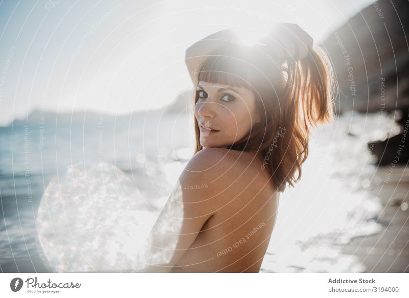 Nackte Frau, die am Strand posiert. Körperhaltung nackt Sonnenlicht Flecken Blick in die Kamera träumen Natur Himmel Schönes Wetter genießen Sommer Model