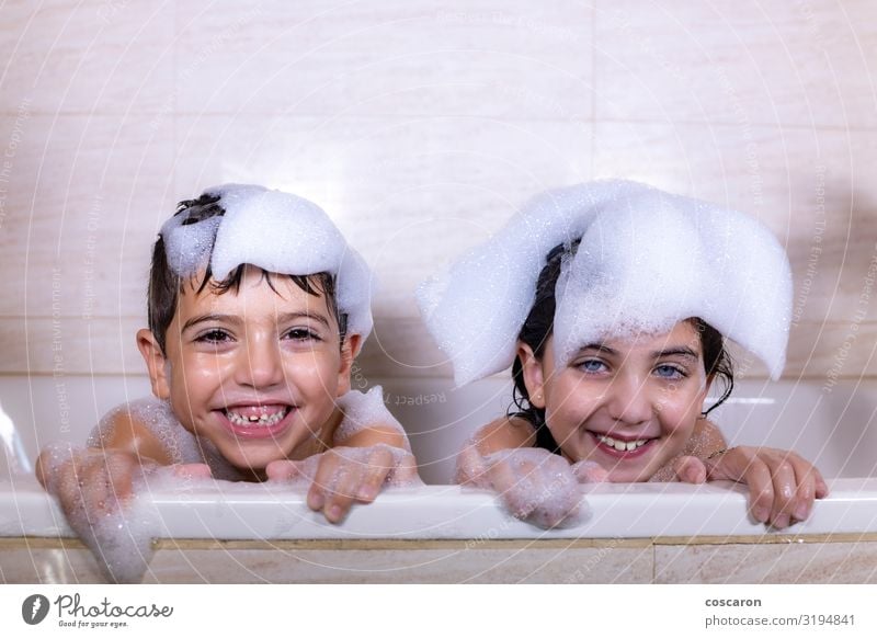 Zwei Kinder beim Baden, die eine Kamera sehen. Lifestyle Freude Glück schön Körperpflege Haare & Frisuren Haut Schwimmen & Baden Kinderspiel Badewanne Mensch