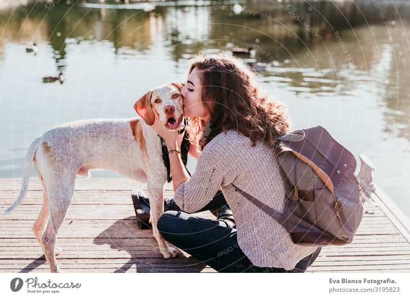 junge Frau, die ihren Hund im Freien in einem Park mit See küsst. sonniger Tag, Herbstzeit Jugendliche Außenaufnahme Liebe Haustier Besitzer Sonnenstrahlen