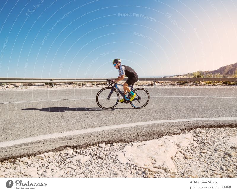 gesunder Mann, der an einem sonnigen Tag auf einer Bergstraße Fahrrad fährt Freizeit & Hobby Athlet Sport Ausritt Rennsport Motorradfahren Außenaufnahme