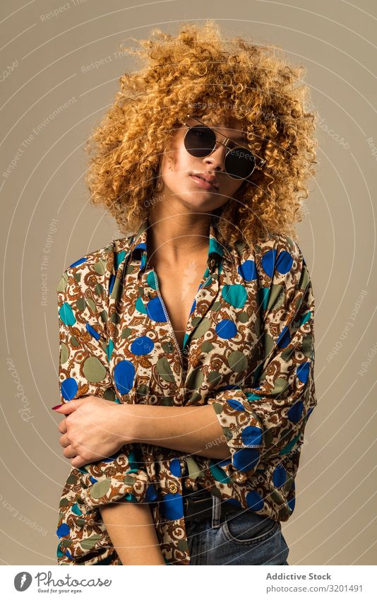 Retro-Frau mit lockigem Haar retro Outfit urwüchsig Sonnenbrille Bluse genießen krause Haare blond Model altehrwürdig Stil trendy Ornament Muster elegant