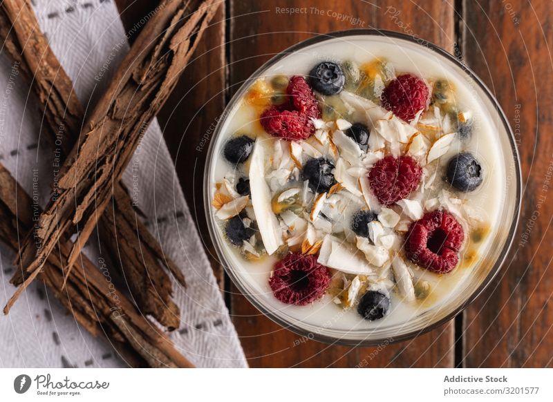 Joghurt in Glasschüssel mit Beeren und Zimtstäbchen Himbeeren Johannisbeeren Flocken Hafer duftig natürlich Vegane Ernährung vegane Milch Lebensmittel Dessert