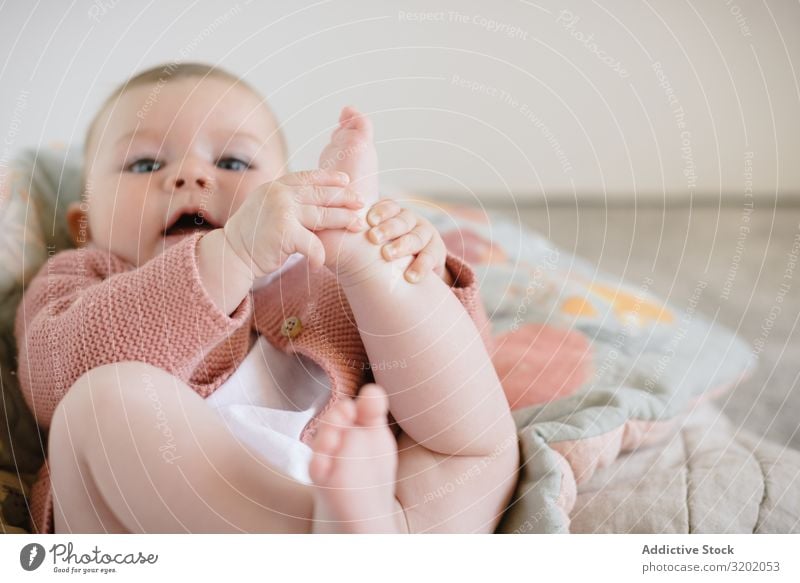 Süßes, liegendes und spielendes Baby mit prallen Beinen Fuß klein Decke Säuglingsalter niedlich gestrickt neugeboren Spielen Freude erkundend schön heiter