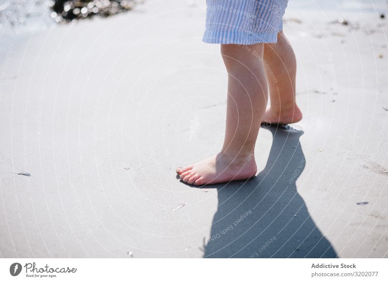 Barfüßiges Kind kurz am Sandstrand klein Strand Barfuß Säuglingsalter niedlich Spielen Freude erkundend schön heiter Kindheit Fundstück hübsch reizvoll