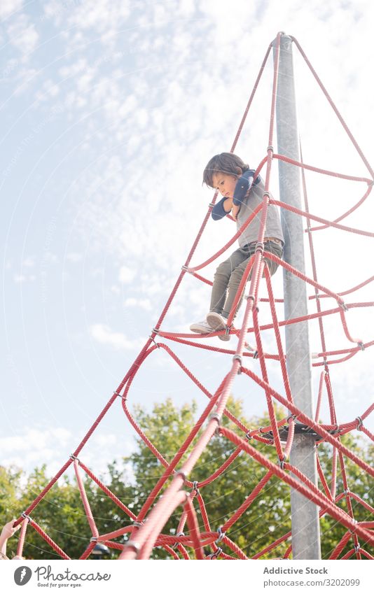 Junge auf Seilkletternetz im Sonnenlicht Spielplatz Tennisnetz Freizeit & Hobby besinnlich erhängen träumen klein Kind Kindheit Aktion spielerisch Klettern