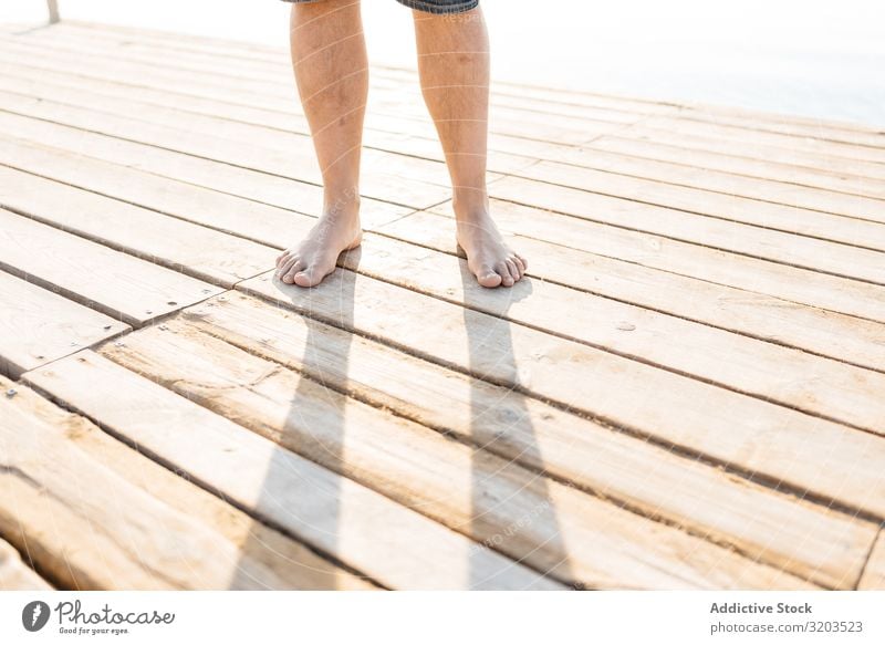 Beine eines Erwachsenen, der auf einem Holzsteg im Sonnenlicht steht Mann stehen Anlegestelle Fuß Beschnittansicht Sommer Zufriedenheit Körperteil Natur