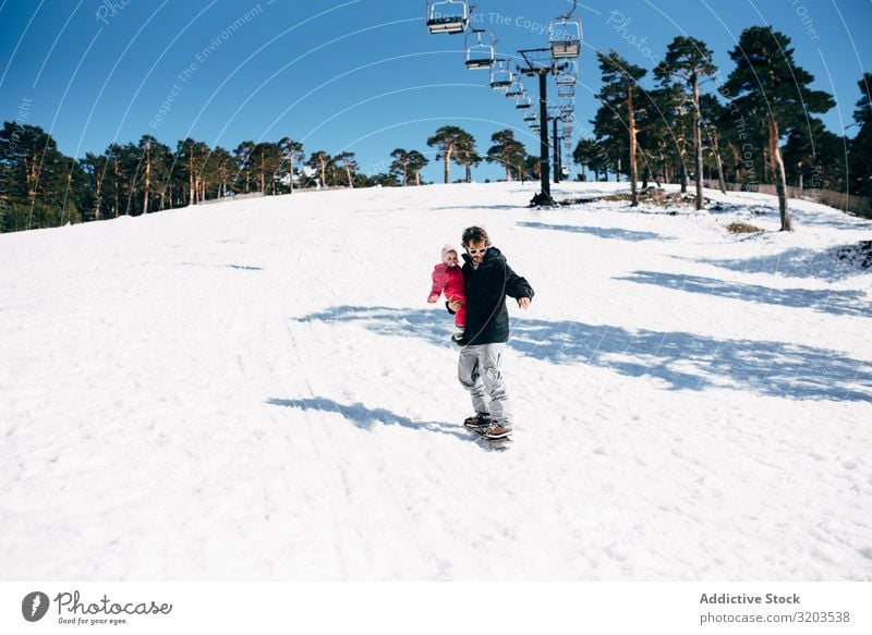 Mann mit Tochter reitet auf Schnee Holzplatte Ausritt Freiheit Kind Natur Kleinkind Winter Rutsche Aktion Berge u. Gebirge Unbekümmertheit erkunden Sport Resort