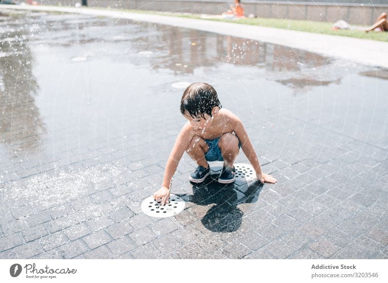 Kind steht in einem Springbrunnen auf der Straße Junge Düsenflugzeug Sommer Im Wasser treiben strömen Park Freude Ferien & Urlaub & Reisen Stadt stehen frisch