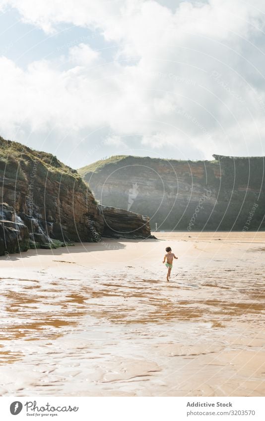 Junge, der am nassen, sonnigen Strand spazieren geht Sonnenlicht Kind Sommer Küste Wasser unschuldig Ferien & Urlaub & Reisen Freizeit & Hobby Baby Spielen