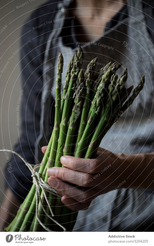 Gesichtslose Frau mit einem Bündel grünen Spargels rustikal Hand Halt organisch Diät Lebensmittel natürlich Ernährung roh Zutaten Vegetarische Ernährung