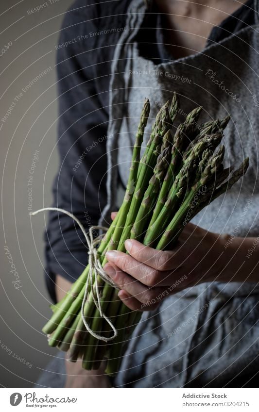 Gesichtslose Frau mit einem Bündel grünen Spargels rustikal Hand Halt organisch Diät Lebensmittel natürlich Ernährung roh Zutaten Vegetarische Ernährung