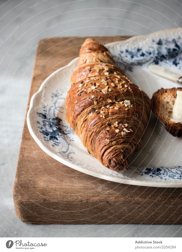 Knuspriges Croissant mit Körnern Getreide lecker Teller Frühstück Snack Lebensmittel Brötchen geschmackvoll Morgen braun Brot frisch Essen zubereiten süß backen