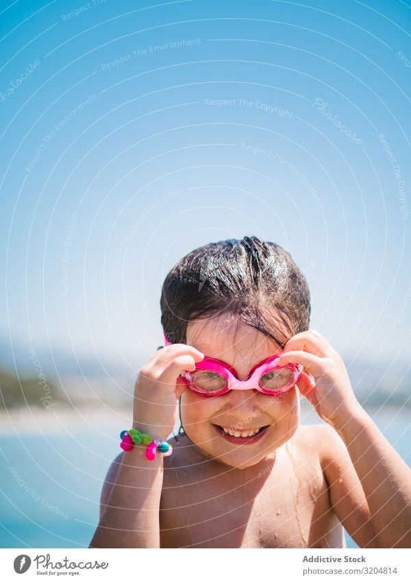 Fröhliches Mädchen mit Schutzbrille nach dem Schwimmen im Meer Schneebrille heiter niedlich Lächeln Kind abfliegend Blauer Himmel Frau Sommer Glück