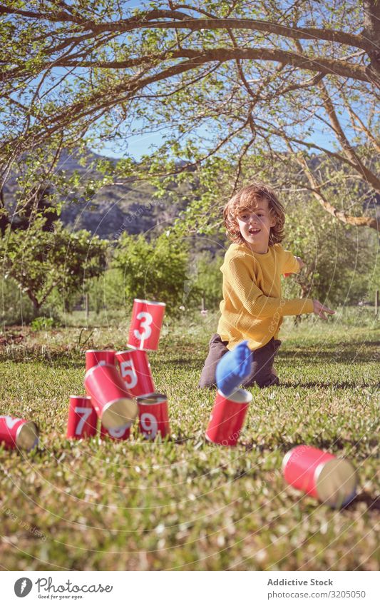 Fröhlicher, süßer Junge spielt im Freien Pyramide Dose Spielen Freude Kindheit klein Mann Mensch Glück lockig reizvoll Aufregung spielerisch niedlich heiter