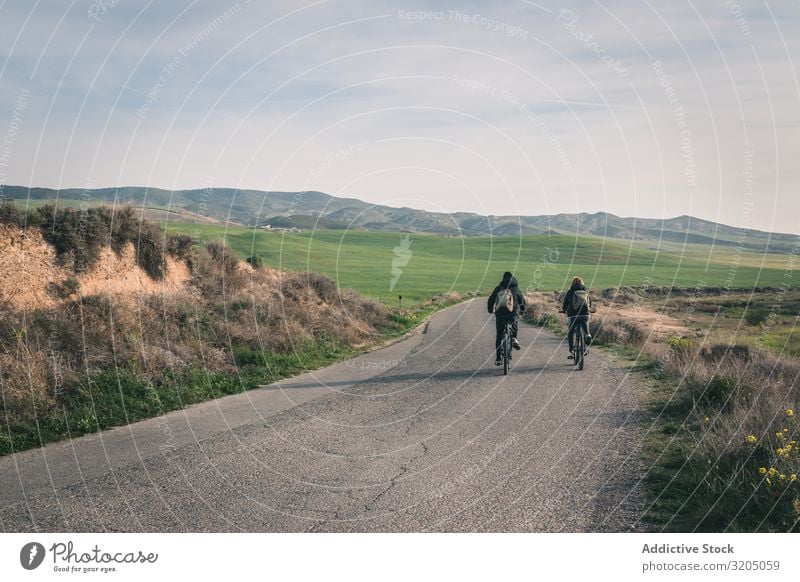 Männer mit dem Fahrrad auf der Straße in den Wüstenhügeln Mann Hügel Landschaft Sand Stein Pflanze Ausflug regenarm Natur Himmel Ferien & Urlaub & Reisen heiß