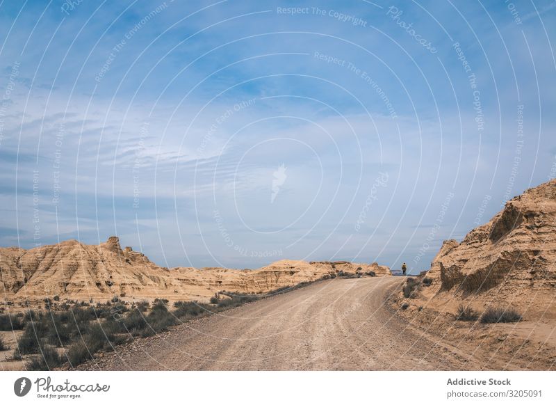 Mann auf der Straße in den Wüstenhügeln Hügel Landschaft Sand Stein Pflanze Ausflug regenarm Natur Himmel Ferien & Urlaub & Reisen heiß Ausflugsziel erkundend