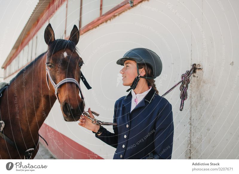 Frau im Jockey-Outfit mit Pferd stehend Kraulen Tier Reiterin Teenager jung Haustier Freund Liebe Streicheln Schutzhelm berühren schön Pflege Säugetier