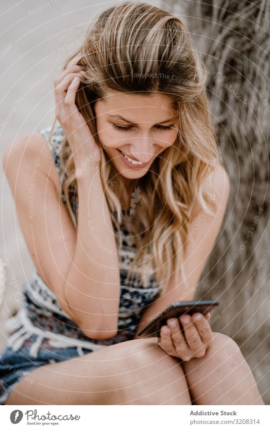 Hübsche Frau benutzt Smartphone am Strand benutzend Sommer Urlaub reisen Mitteilung Erholung Feiertag Resort jung Person attraktiv schön glamourös blond lässig