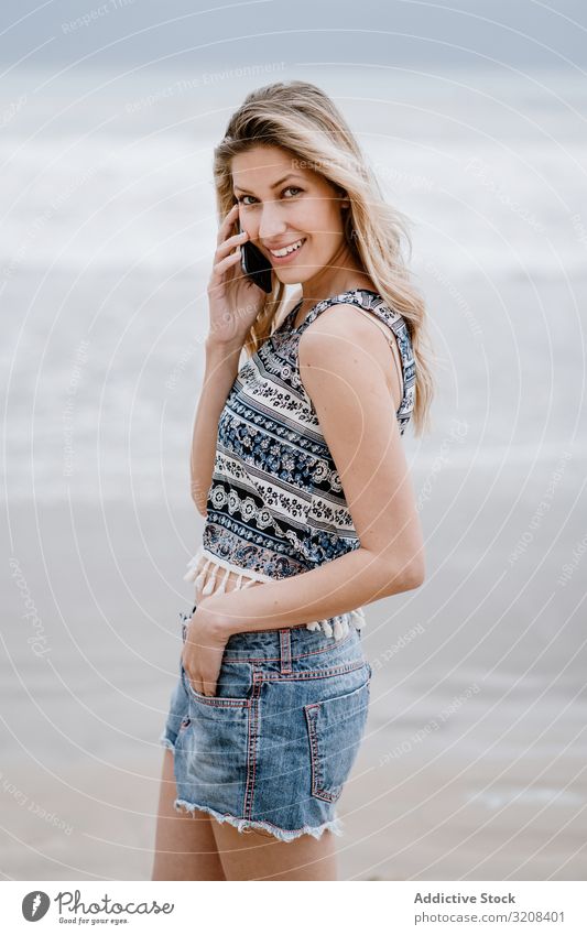 Hübsche Frau beim Telefonieren mit dem Handy Smartphone MEER Strand sprechend Sommer Urlaub reisen Mitteilung Feiertag jung attraktiv schön blond lässig Top