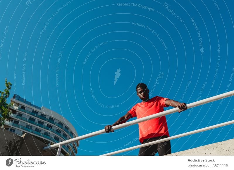 Afroamerikanischer junger Mann auf Brücke unter blauem Himmel urban sportlich Inspiration entschlossen Gesundheit muskulös Blauer Himmel ethnisch schwarz